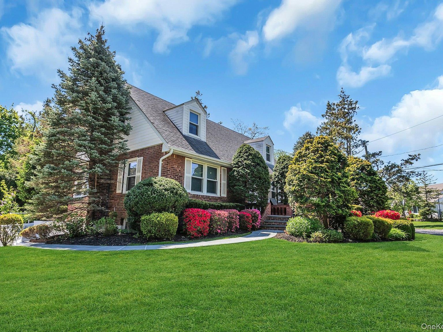 Front entry of the home with manicured boxwoods and stone pavers