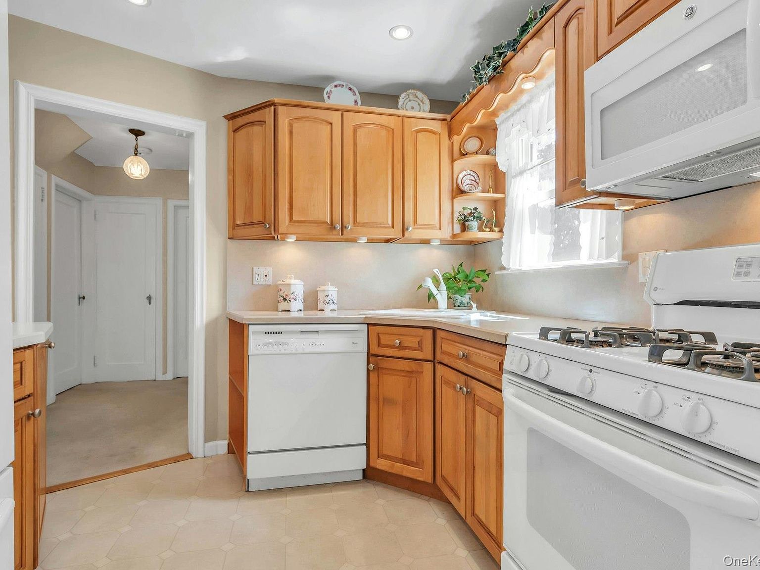 Eat-in kitchen with gas range, wood cabinetry, and an adjoining hallway